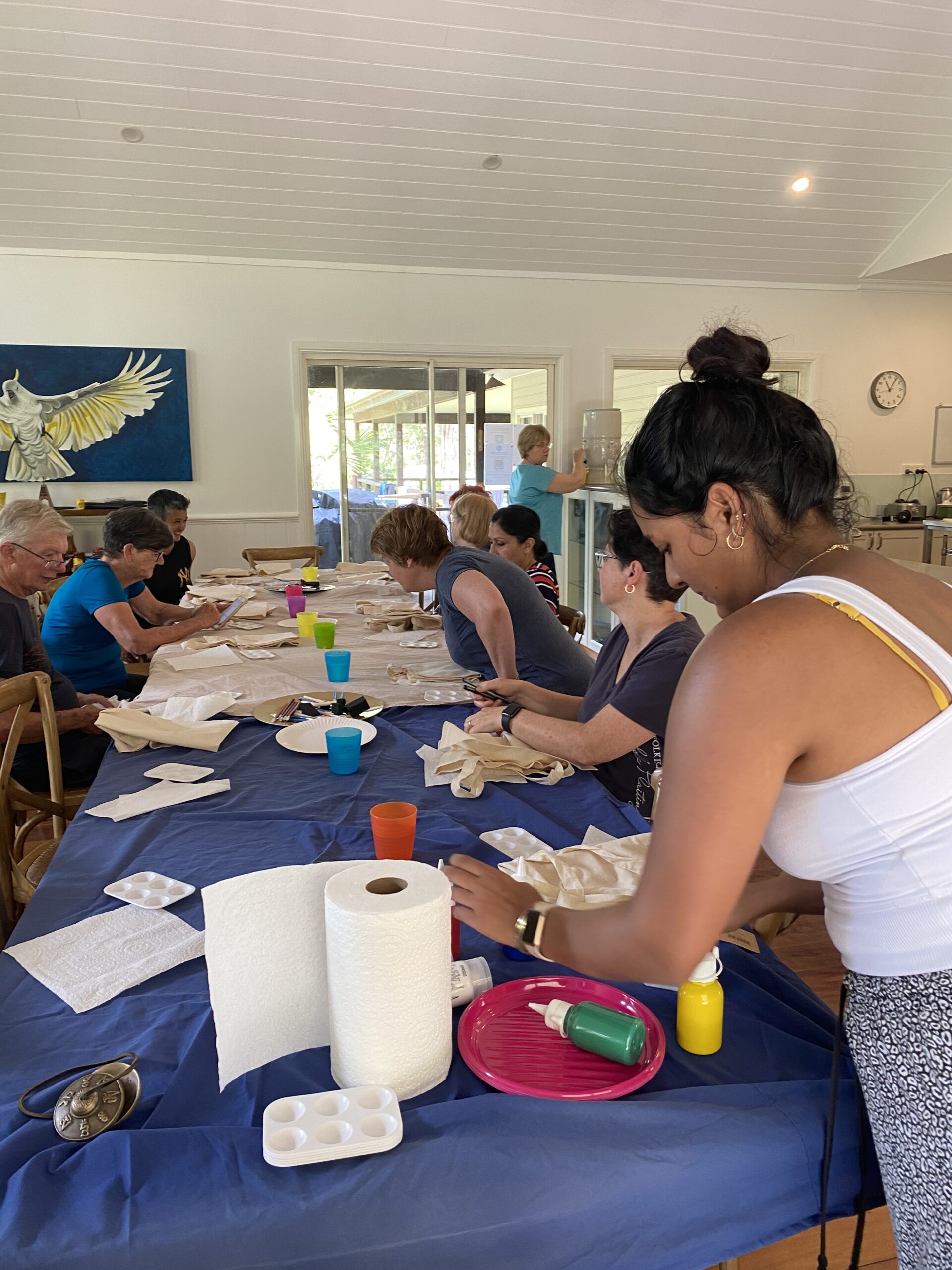 Participants engaged in a mindful creative workshop at the Mystique Moksha Samatvam Retreat; a group gathered around a long table at Yanada Retreat, NSW, participating in hands-on activities as part of the holistic wellness program.